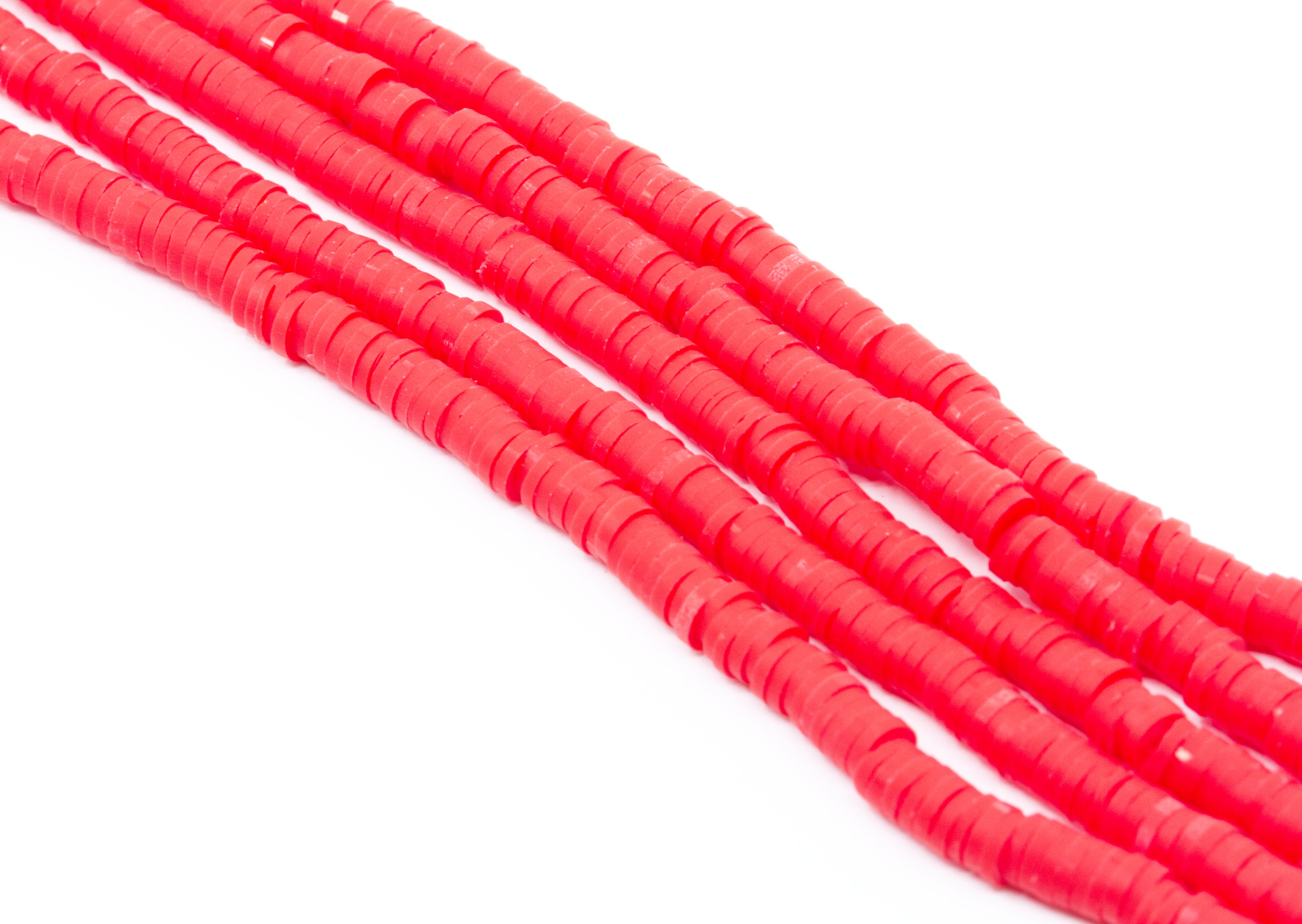 Several strands of bright red polymer clay disc beads arranged diagonally on a plain white background.