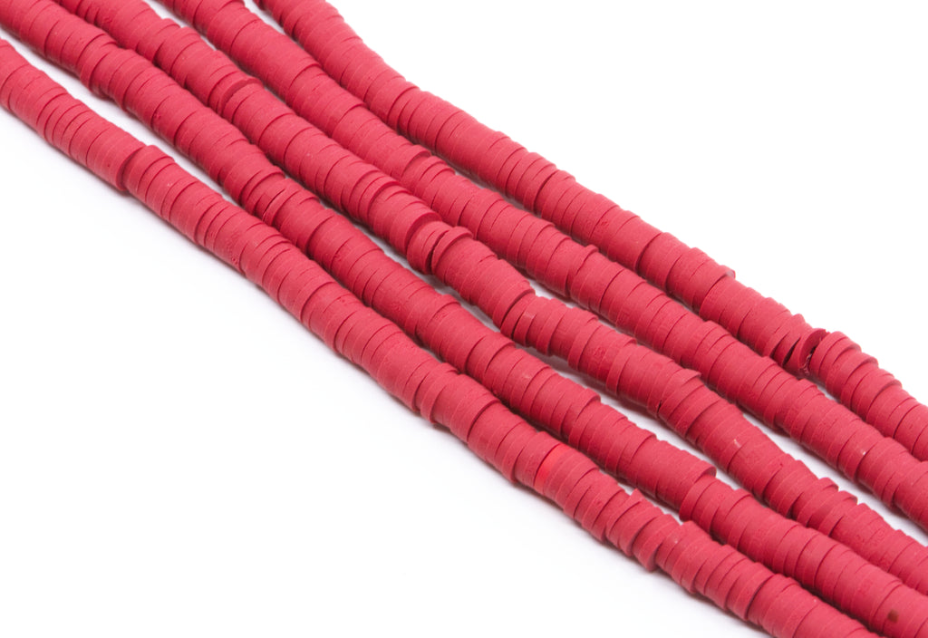Multiple strands of red polymer clay disc beads arranged diagonally on a plain white background.