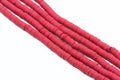 Multiple strands of red polymer clay disc beads arranged diagonally on a plain white background.