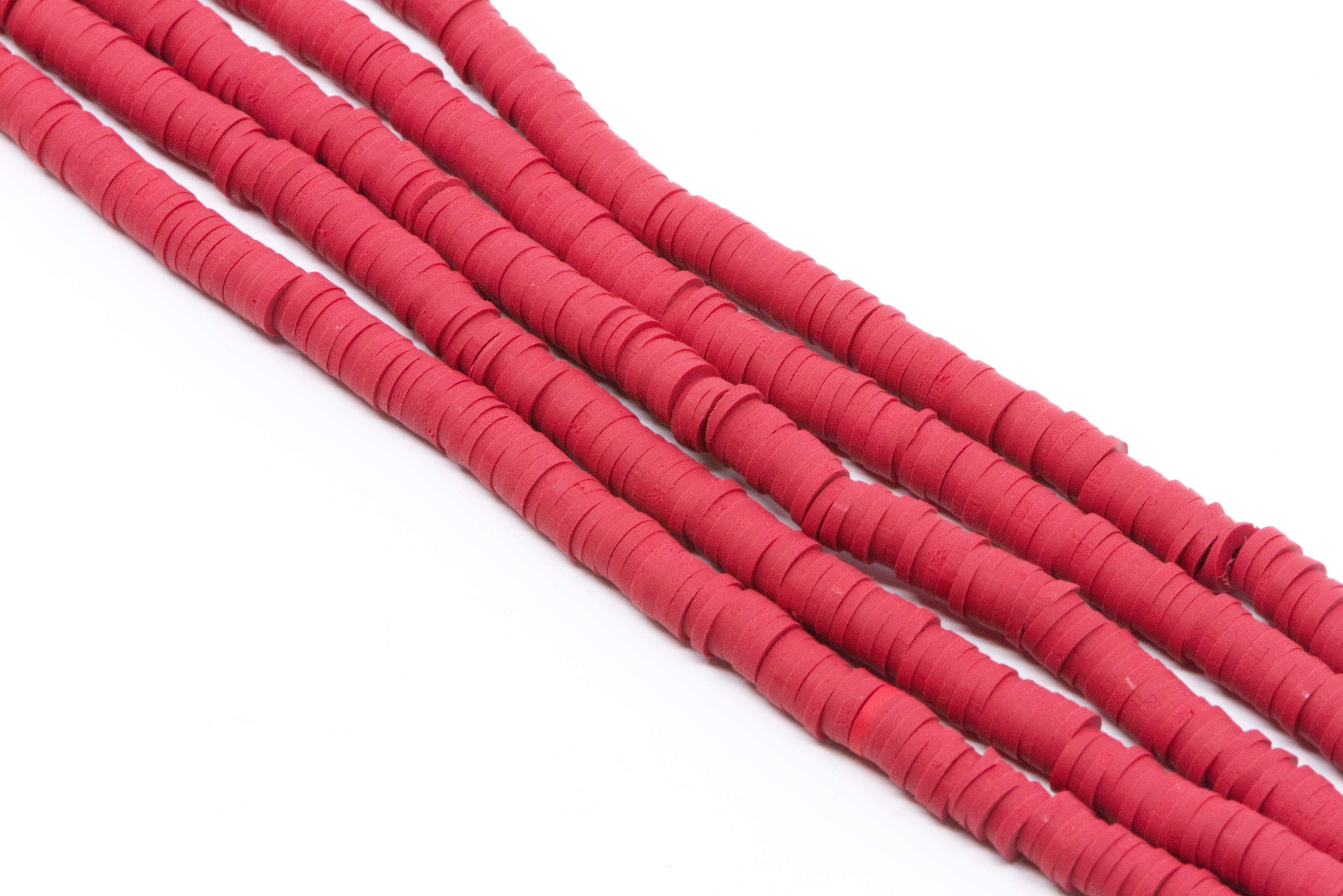 Multiple strands of red polymer clay disc beads arranged diagonally on a plain white background.