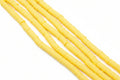 Five strands of golden orange polymer clay disc beads arranged diagonally on a white background.