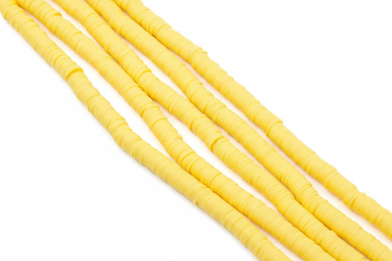 Five strands of golden orange polymer clay disc beads arranged diagonally on a white background.