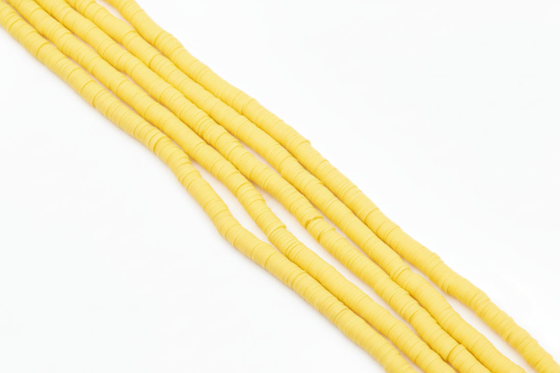 Five strands of golden orange polymer clay disc beads arranged diagonally on a white background.