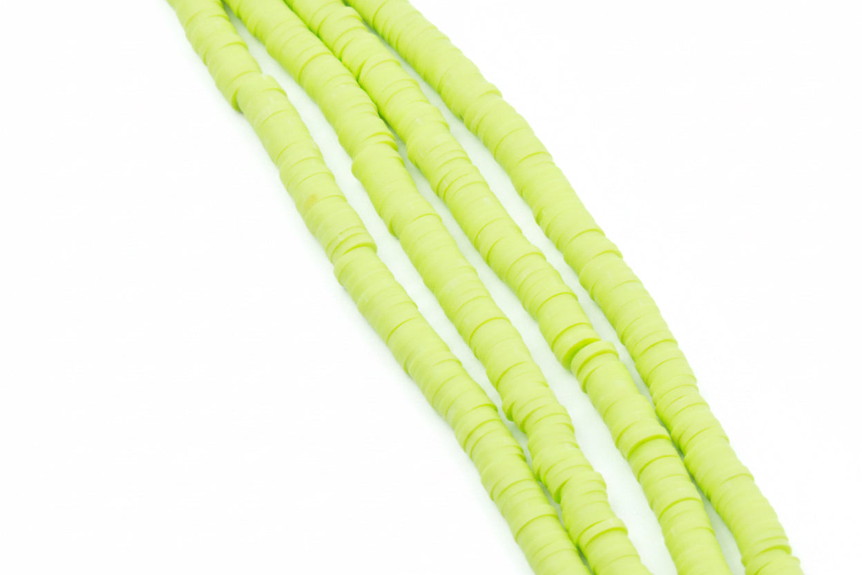 four strands of green polymer clay beads shown diagonally on a white background 