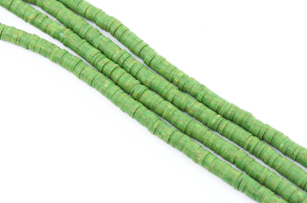 multiple strand of green polymer clay disc beads photographed diagonally on a plain white background.