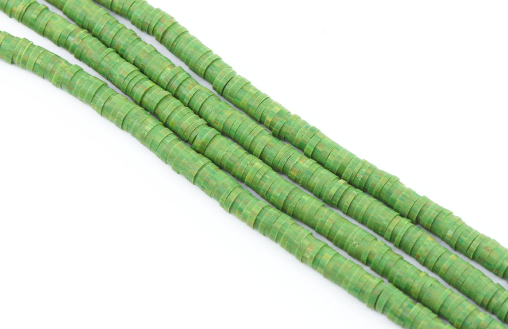 multiple strand of green polymer clay disc beads photographed diagonally on a plain white background.