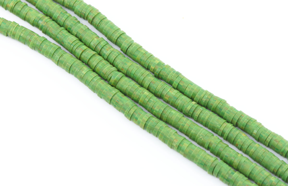 multiple strand of green polymer clay disc beads photographed diagonally on a plain white background.
