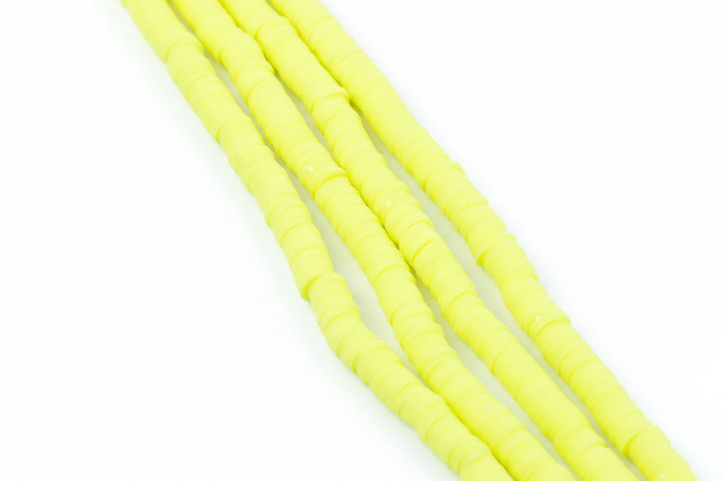 Four strands of bright neon yellow polymer clay disc beads arranged diagonally on a white background
