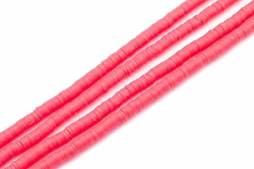 A close-up of several strands of bright pink polymer clay disc beads arranged diagonally on a plain white background.