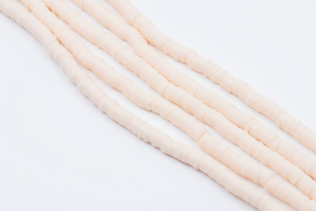 multiple strands of light peach colored polymer clay disc beads  arranged diagonally on a white background 