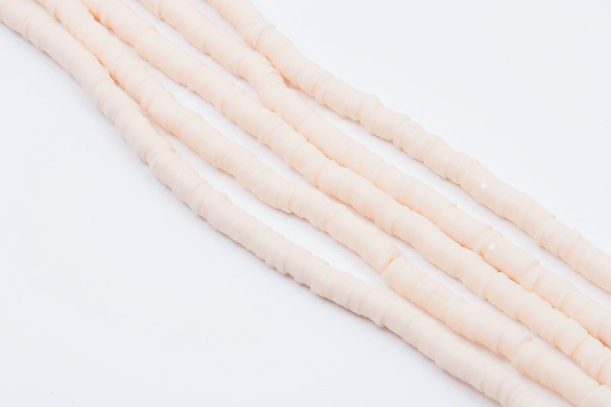 multiple strands of light peach colored polymer clay disc beads  arranged diagonally on a white background 