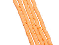 A close-up of several strands of orange polymer clay disc beads arranged diagonally on a white background.