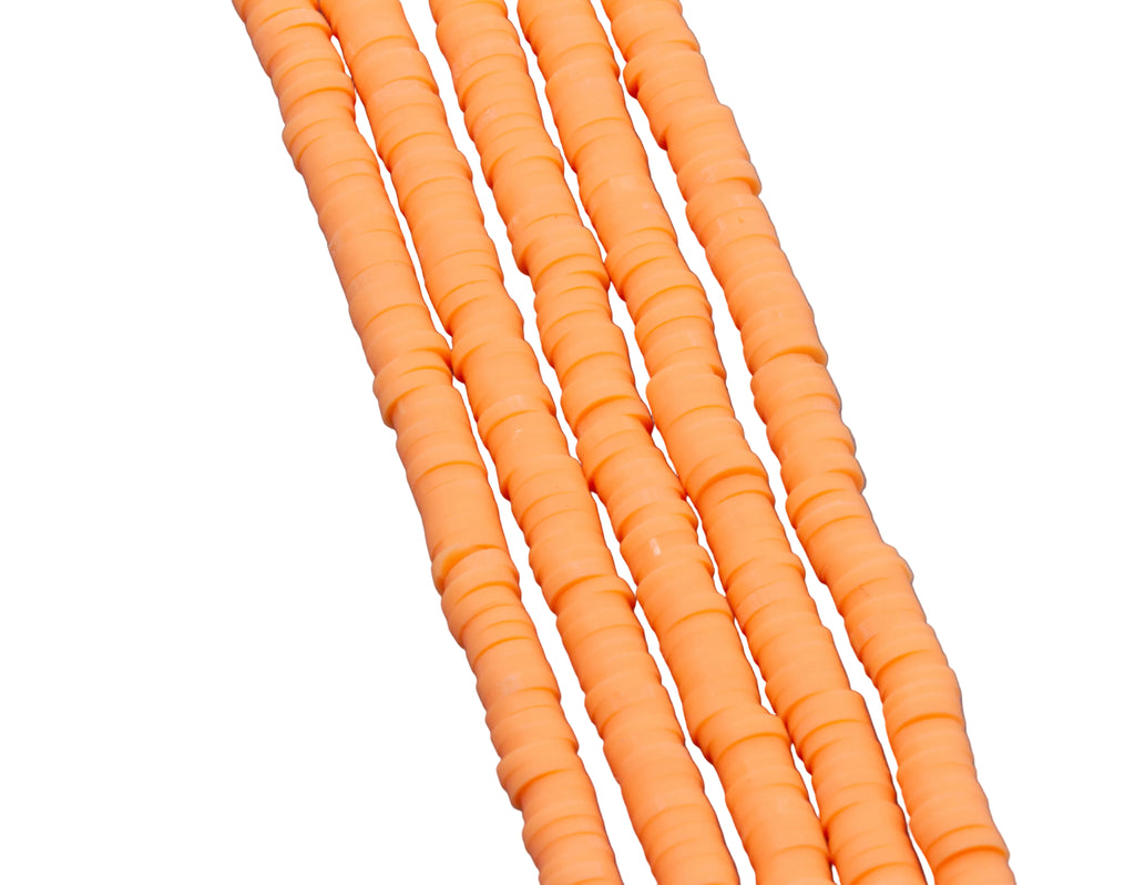 A close-up of several strands of orange polymer clay disc beads arranged diagonally on a white background.