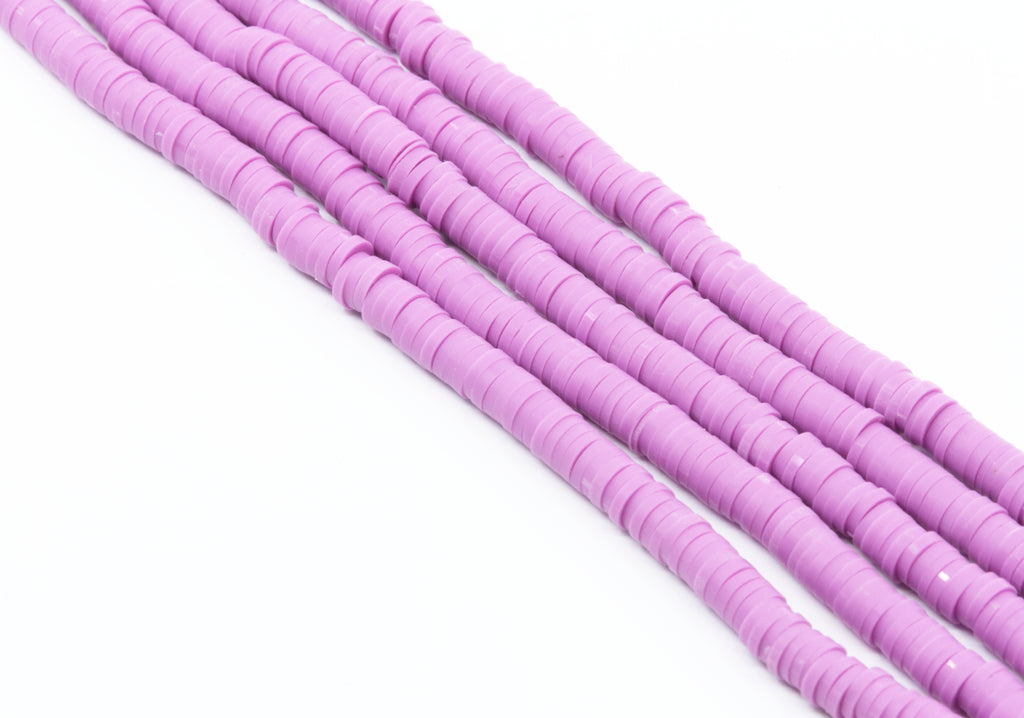 multiple strands of purple polymer clay disc beads arranged diagonally on a plain white background.