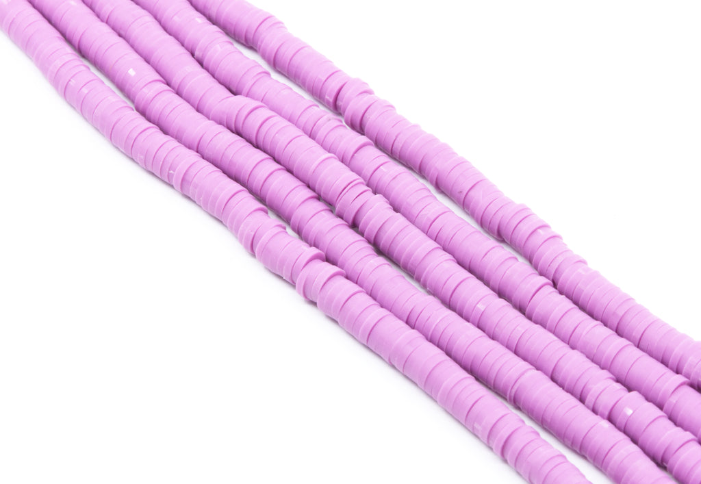 multiple strands of purple polymer clay disc beads arranged diagonally on a plain white background.
