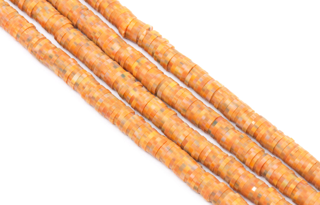 strands of orange speckled polymer clay beads on a white background. 