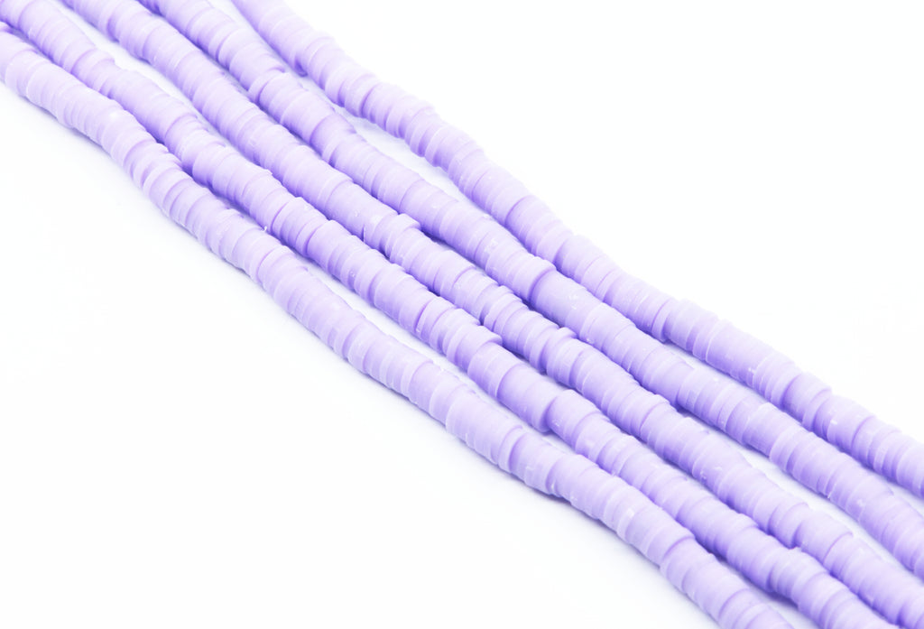 multiple strands of purple polymer clay beads arranged diagonally on a plain white background.