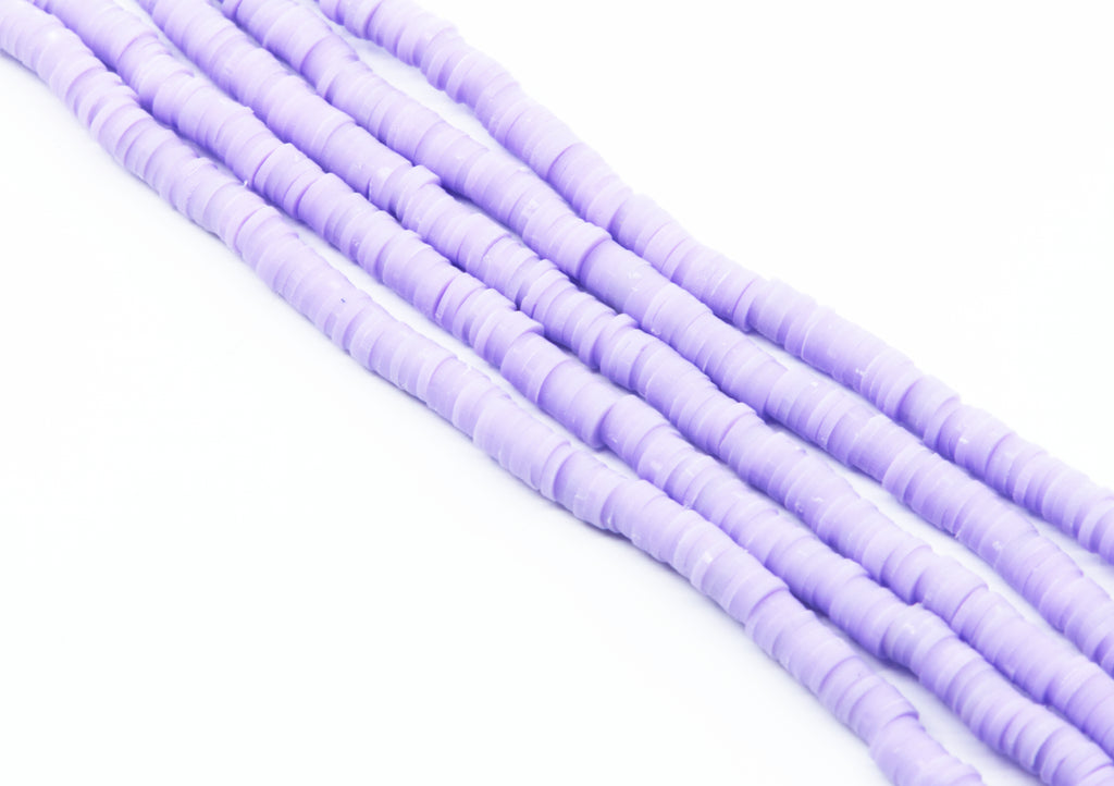 multiple strands of purple polymer clay beads arranged diagonally on a plain white background.