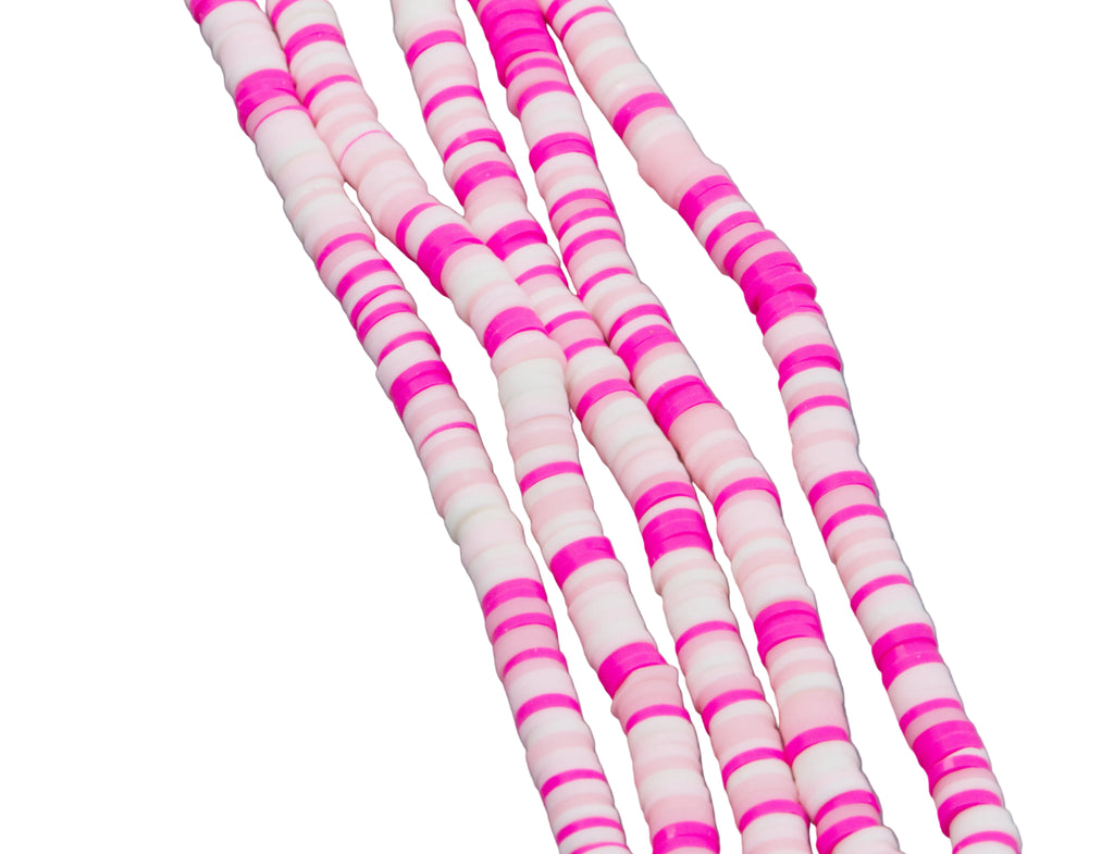 Pink and white polymer clay disc beads arranged in diagonal strands on a solid white background.