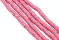 Several strands of red polymer clay disc beads arranged diagonally on a plain white background.
