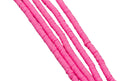 multiples strand of pink polymer clay disc beads photographed diagonally against a solid white background.