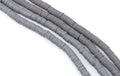 Gray polymer clay beads arranged in diagonal strands on a plain white background.
