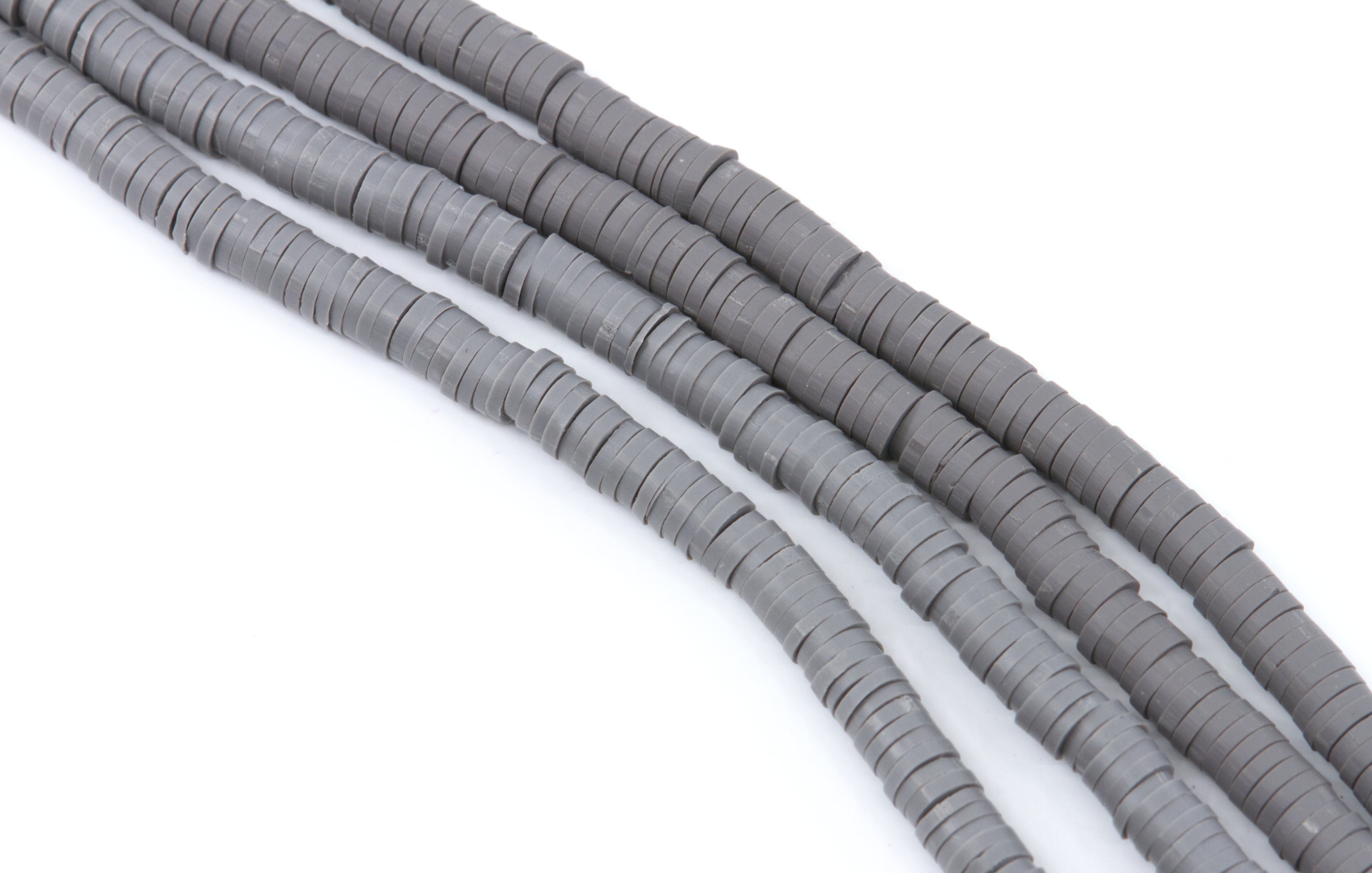 Gray polymer clay beads arranged in diagonal strands on a plain white background.