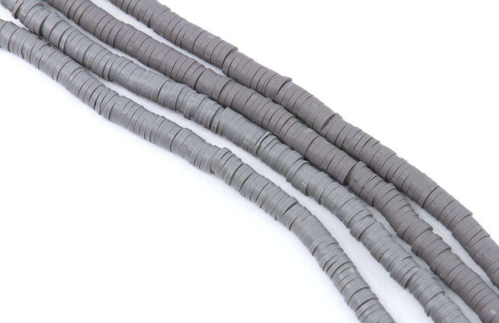 Gray polymer clay beads arranged in diagonal strands on a plain white background.