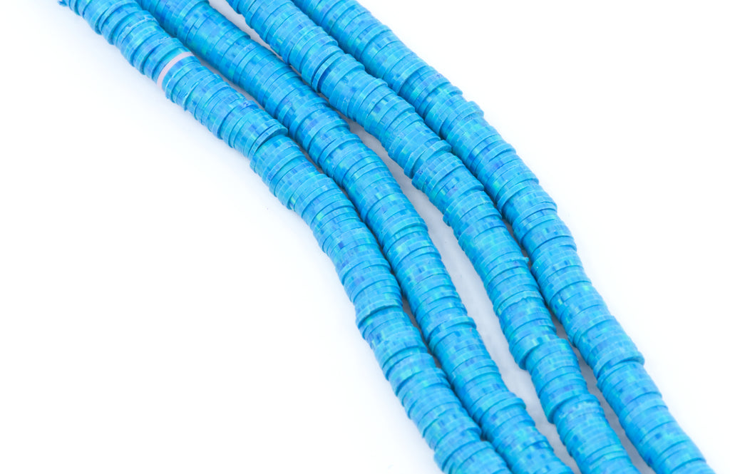 Four strands of bright blu and green speckled polymer clay disc beads arranged diagonally on a plain white background.