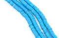 Four strands of bright blu and green speckled polymer clay disc beads arranged diagonally on a plain white background.