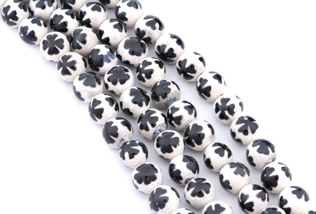Four strands of round white beads with a blue clover-like pattern, arranged diagonally on a white background.