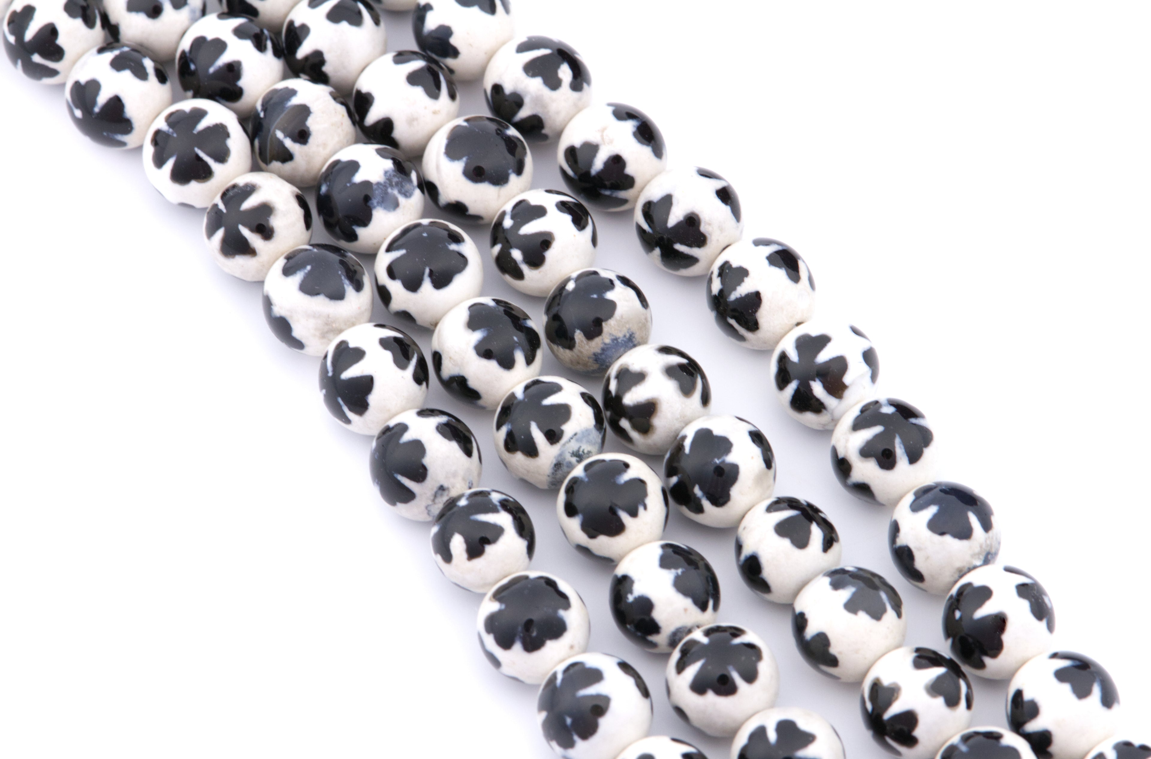 Four strands of round white beads with a blue clover-like pattern, arranged diagonally on a white background.