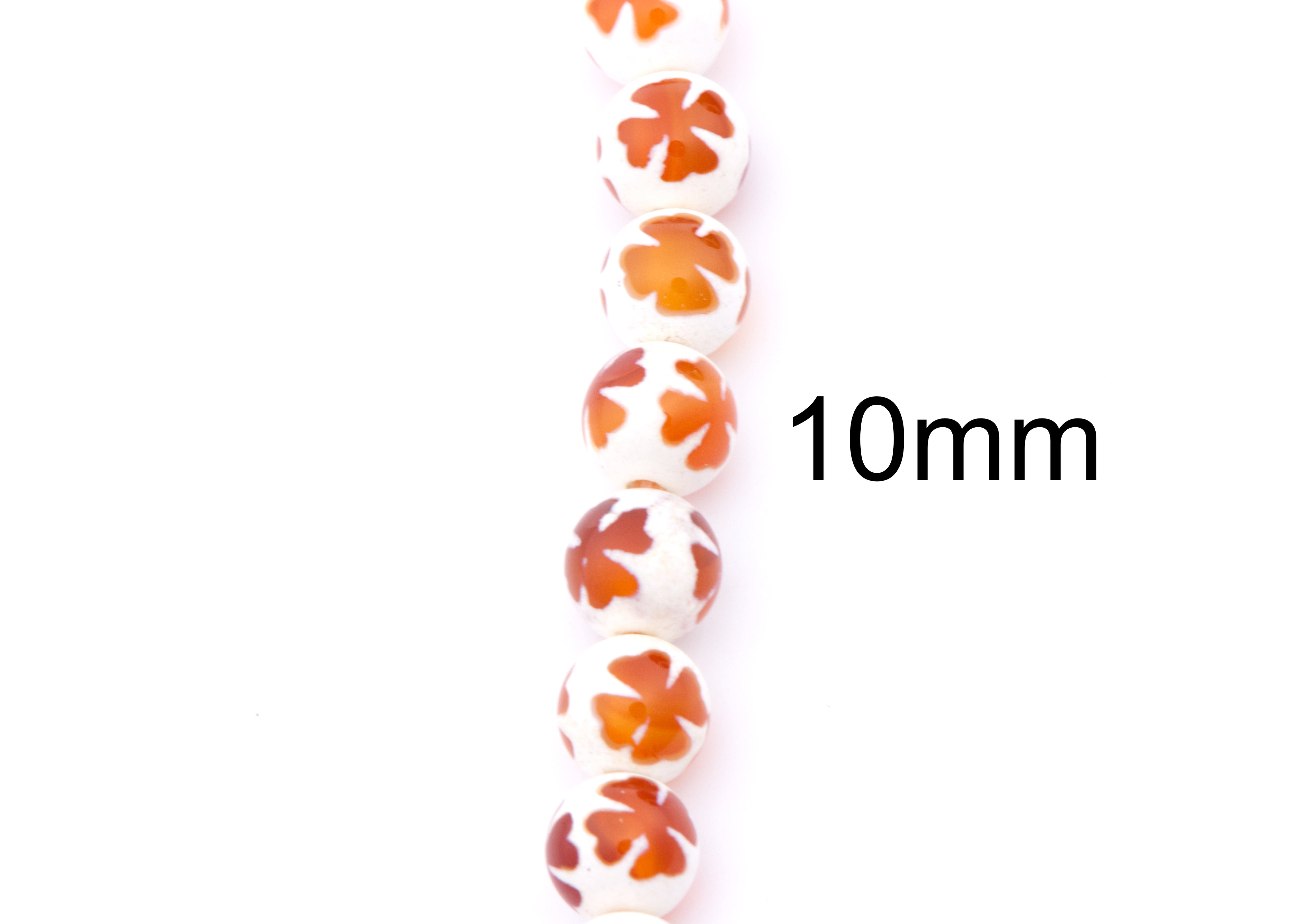 A vertical strand of 10mm round beads on a white background, featuring a white base with a central orange clover design. 