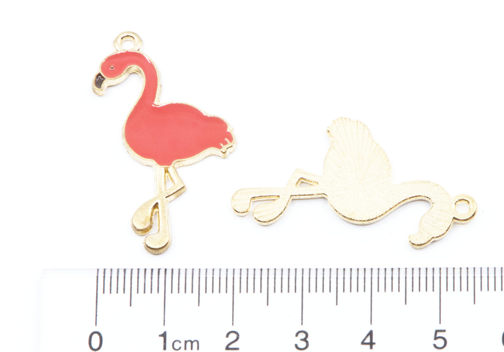 Two flamingo-shaped jewelry charms shown on a white background with a cm ruler at the bottom for scale. 