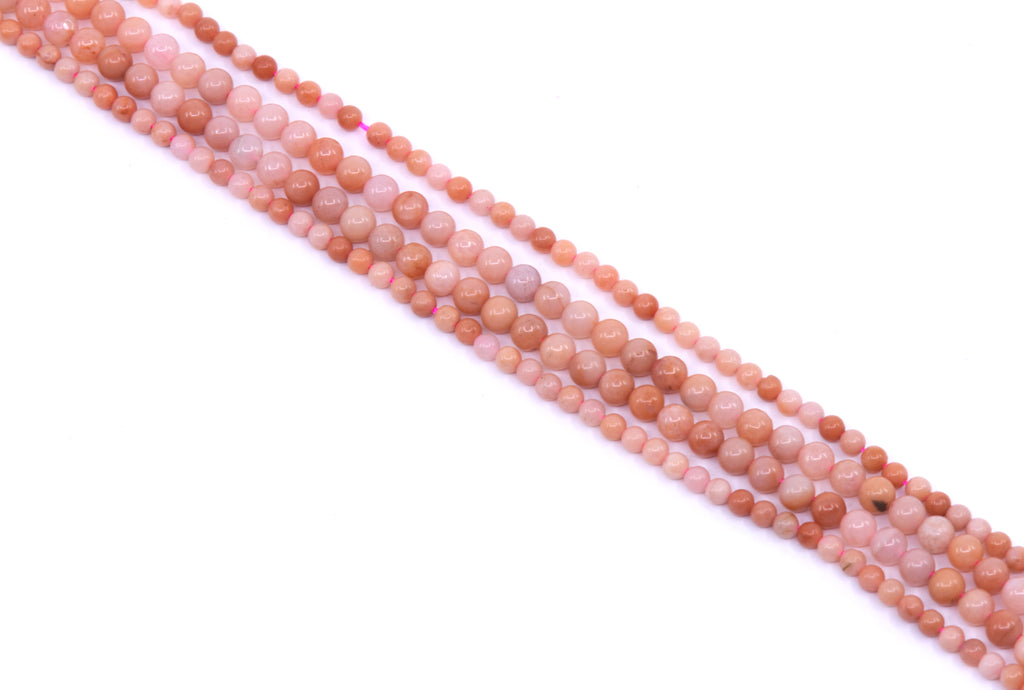 four strands of dark pink aventurine beads arranged diagonally on a white background.