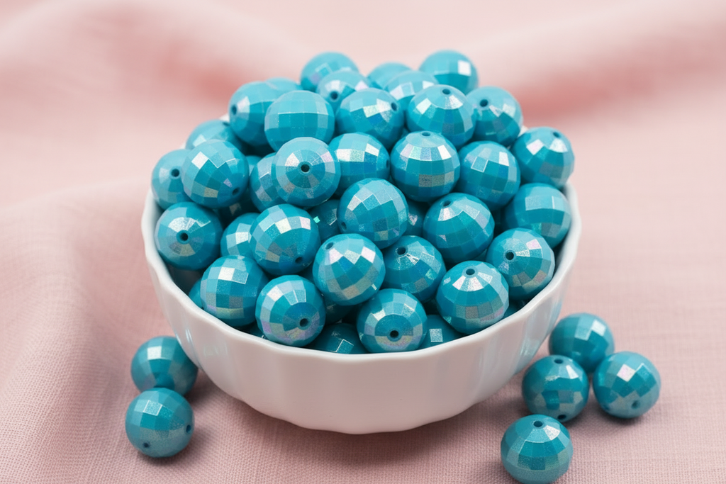 light blue faceted beads in a white bowl on a pink background