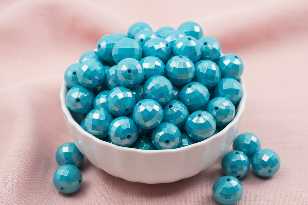 light blue faceted beads in a white bowl on a pink background