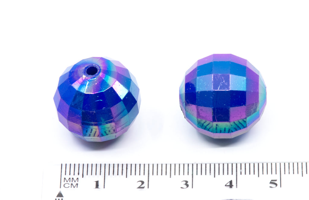 Two blue faceted beads with a ruler for scale on a white background