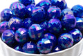 Blue faceted beads in a white bowl on a white background