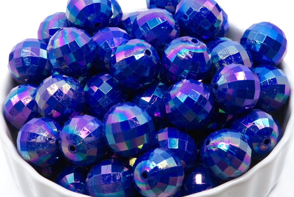 Blue faceted beads in a white bowl on a white background 