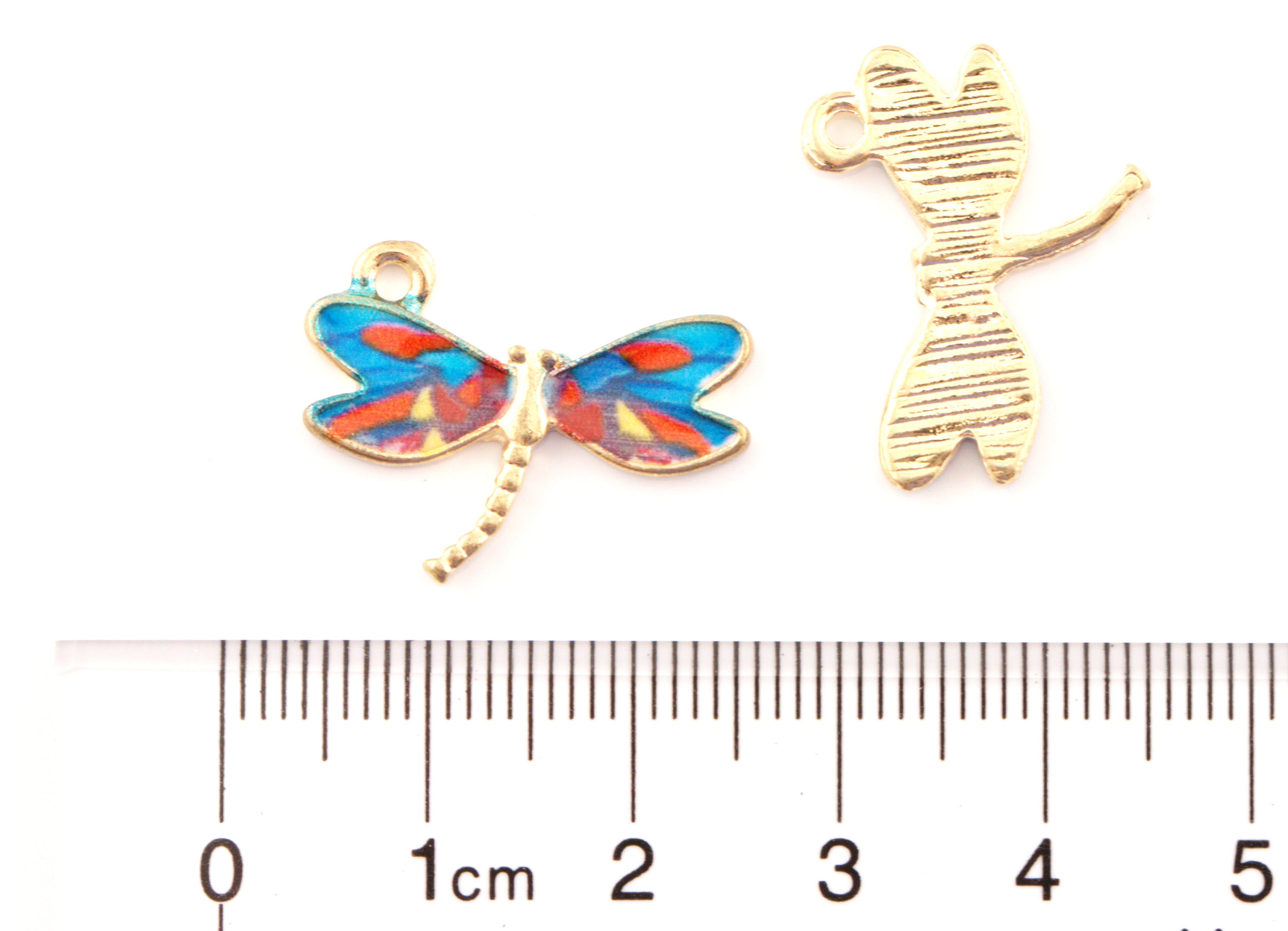 Two blue dragonfly jewelry charms on a white background. A cm ruler at the bottom shows scale.