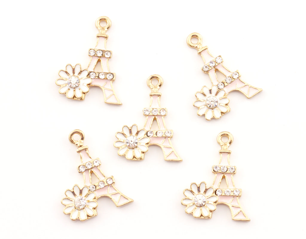 Five pink Eiffel Tower charms, each decorated with a small white flower and clear rhinestones, arranged on a plain white background.