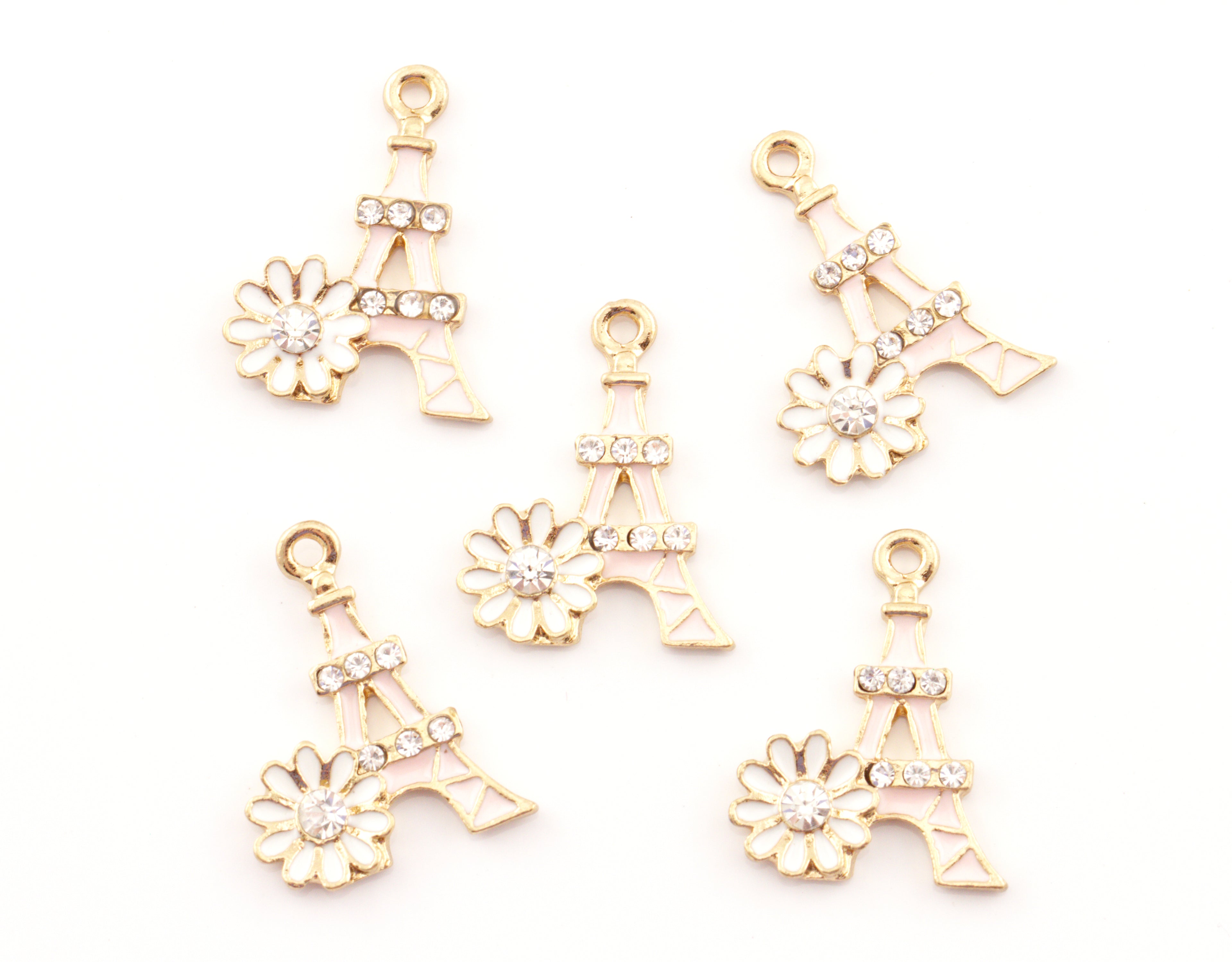 Five pink Eiffel Tower charms, each decorated with a small white flower and clear rhinestones, arranged on a plain white background.