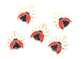 Five ladybug charms with gold-tone metal outlines, red and black enamel, and small white flower petals, arranged on a plain white background.
