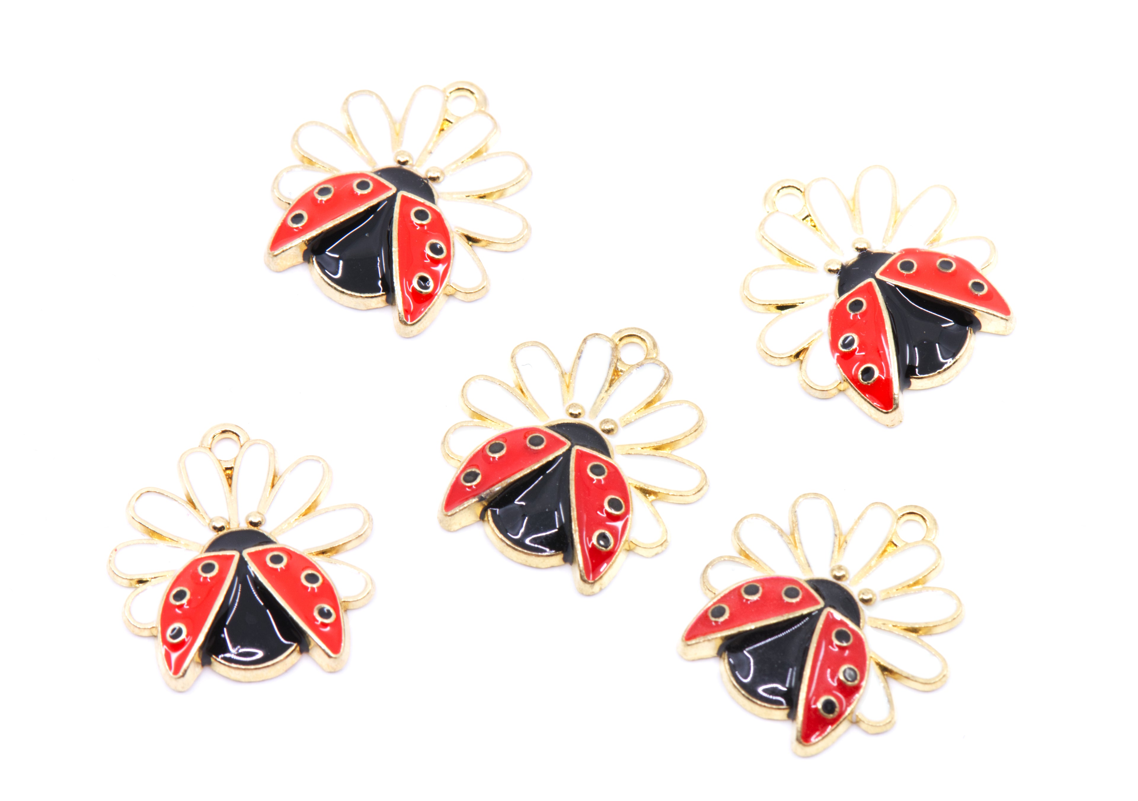 Five ladybug charms with gold-tone metal outlines, red and black enamel, and small white flower petals, arranged on a plain white background.