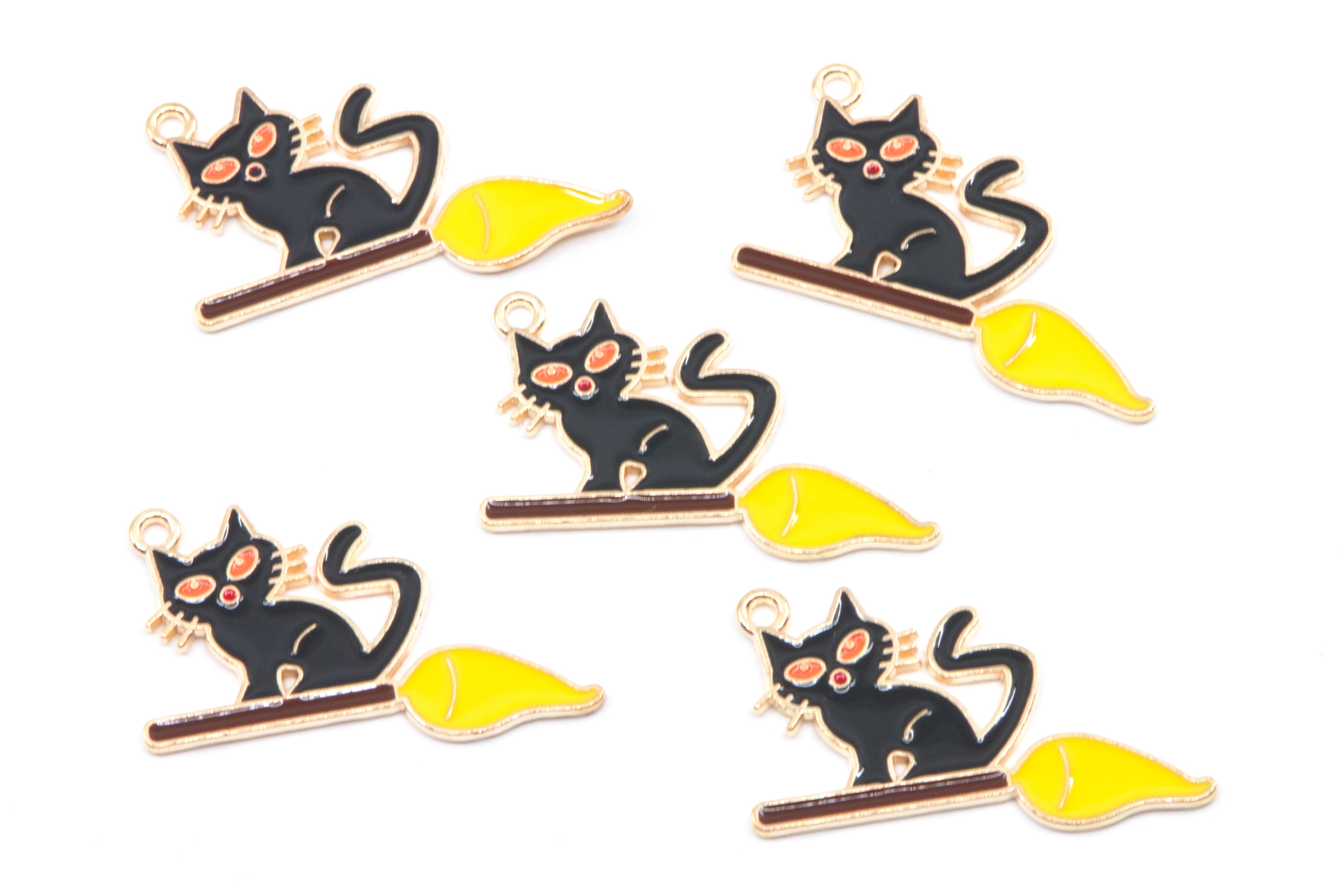 Five identical enamel charms of a black cat sitting on a yellow broomstick, arranged on a plain white background.