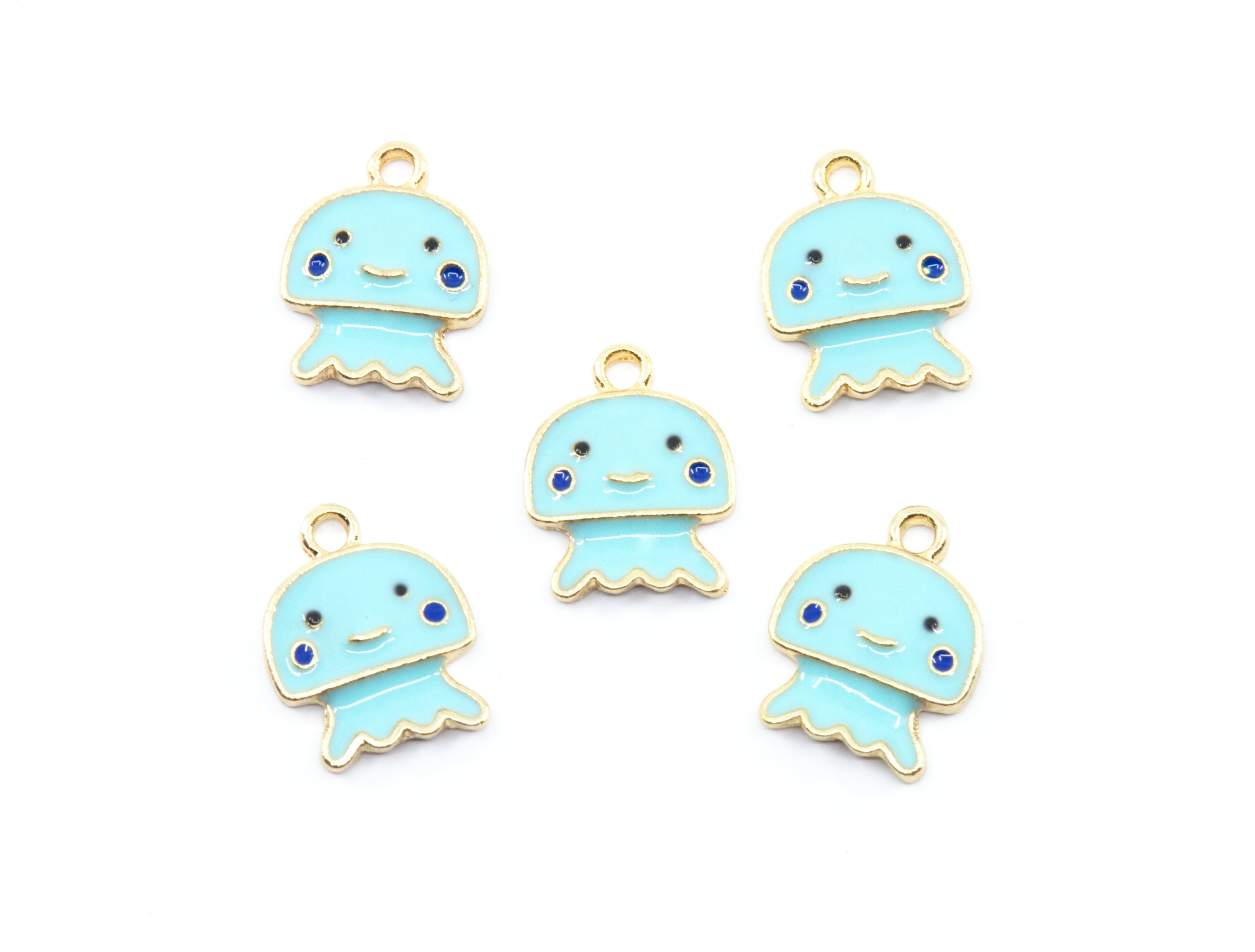 Five light blue jellyfish charms with gold-tone metal borders, small blue gemstone eyes, and black facial features, arranged on a plain white background.