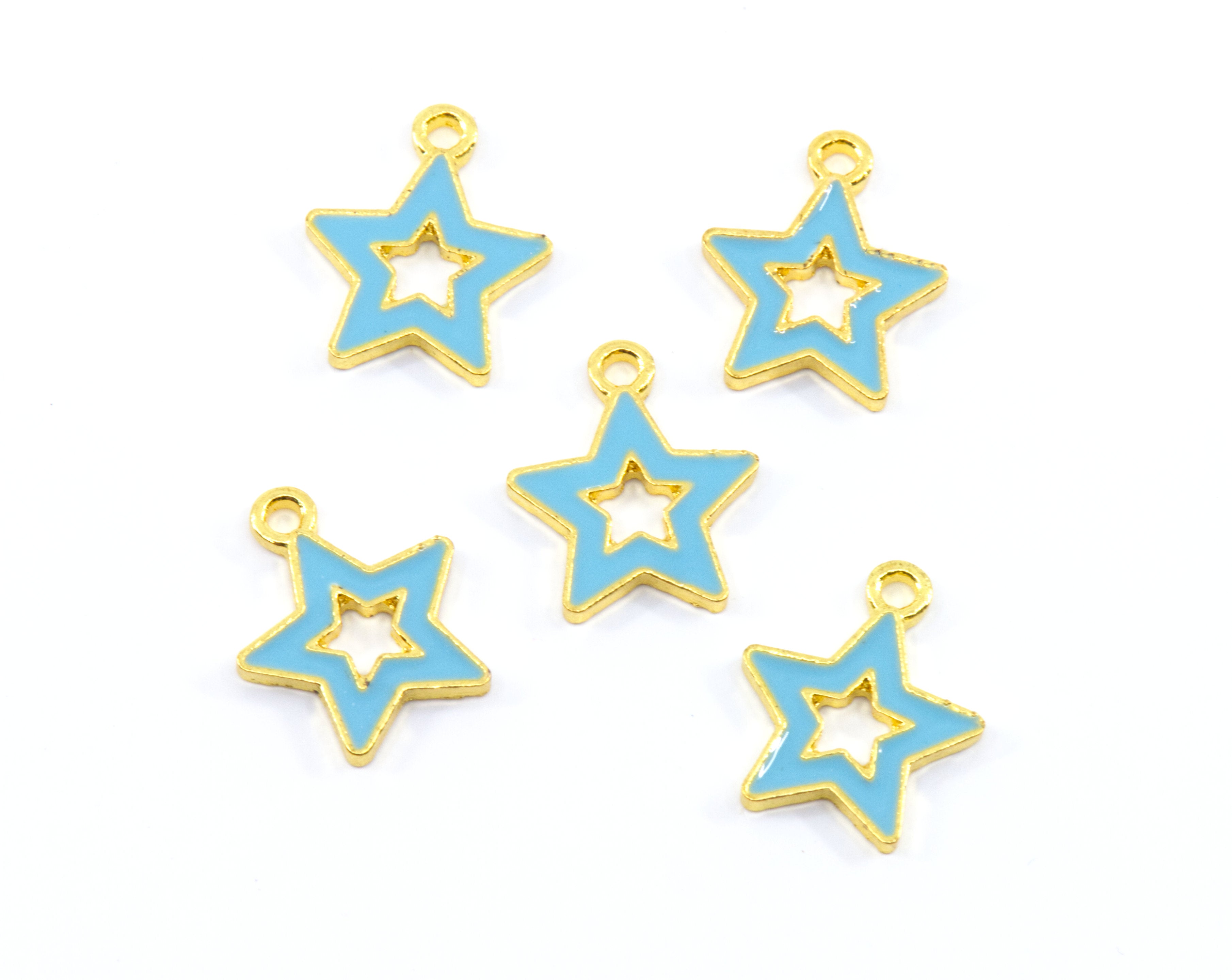 Five star-shaped jewelry charms with light blue enamel and gold metal trim, arranged on a plain white background.