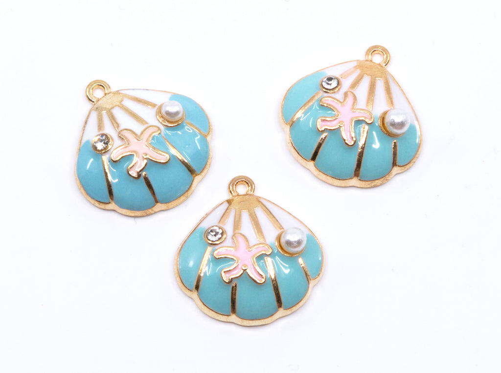 Three seashell-shaped jewelry charms with turquoise blue enamel, gold-tone metal borders, pink starfish details, and small pearl accents on a white background.