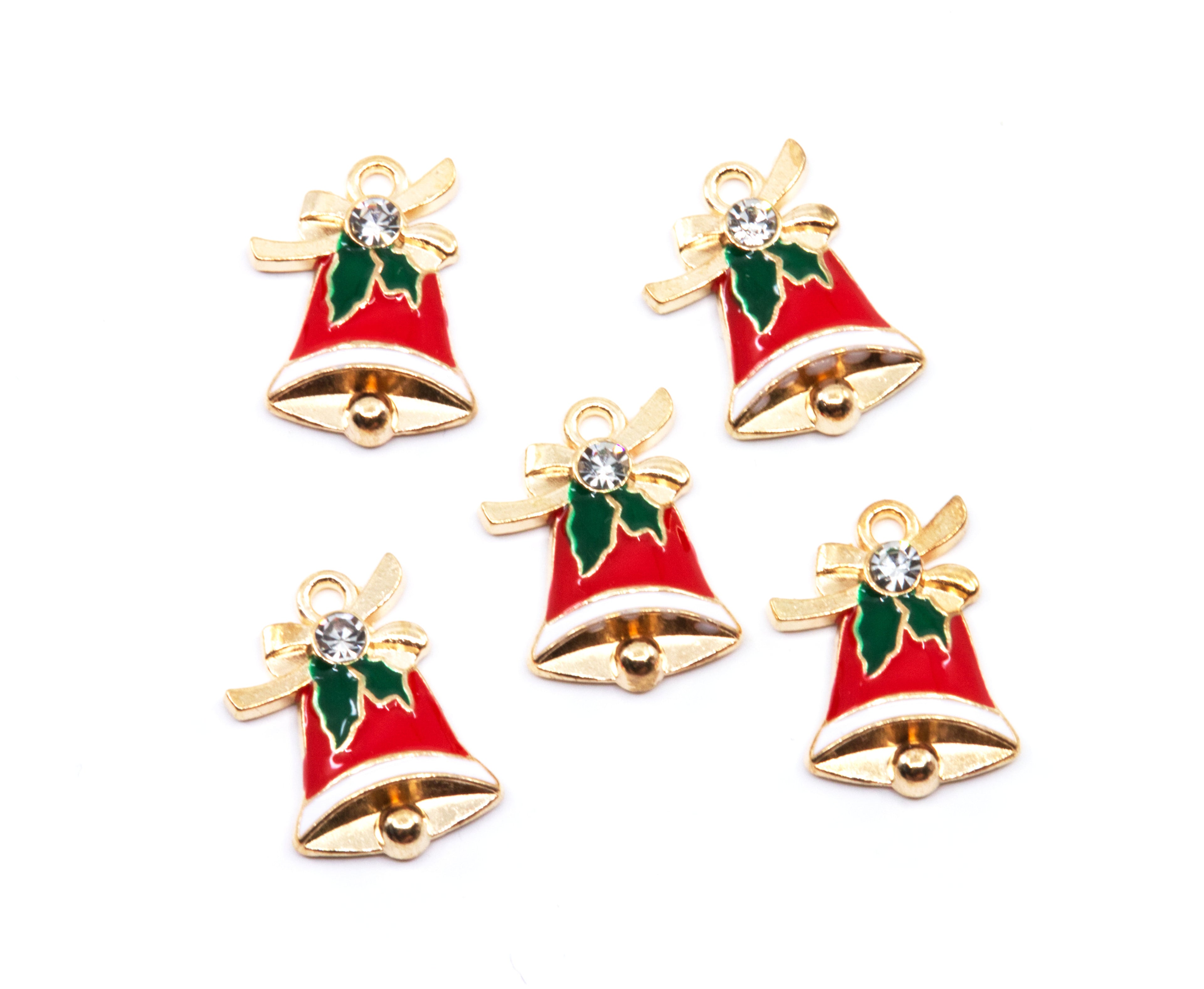 Five Christmas bell charms with red enamel, gold-tone metal borders, green holly leaves, and a clear rhinestone, arranged on a white background.